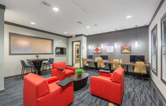 a lounge area with red chairs and a table with a television