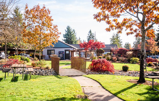 Tacoma Apartments - The Lodge at Madrona Apartments - Community Picnic Tables and Clubhouse Exterior