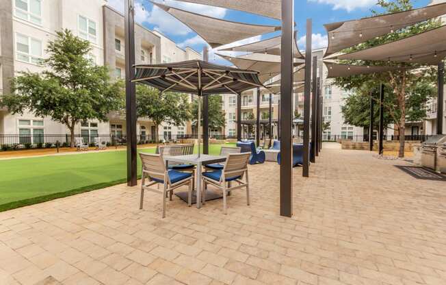 a patio with a table and chairs and umbrellas in front of a building