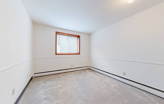 a bedroom with white walls and a window