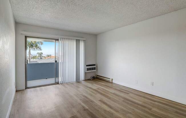 A room with a sliding glass door leading to a balcony.