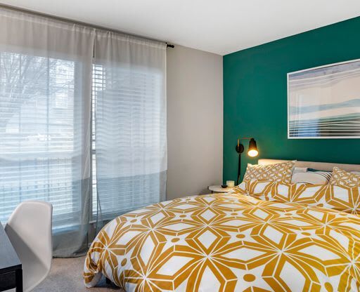 a bedroom with a green wall and a yellow and white bedspread at Elme Alexandria, Alexandria