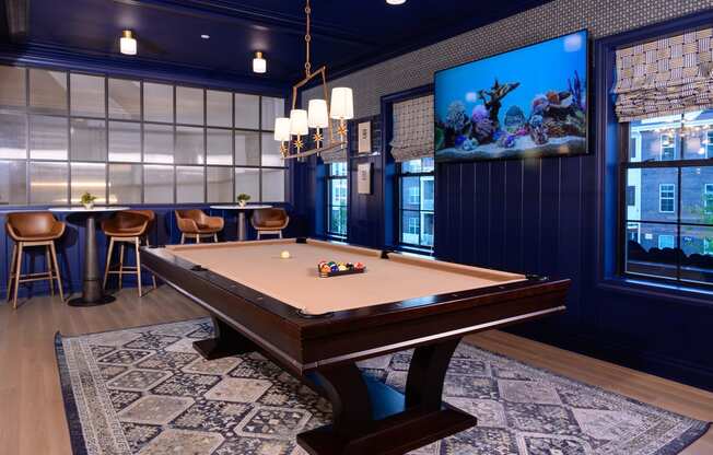 A pool table is in the middle of a room with a blue wall and a television.