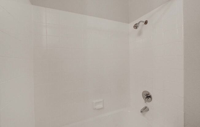 A white bathroom with a shower and faucet.