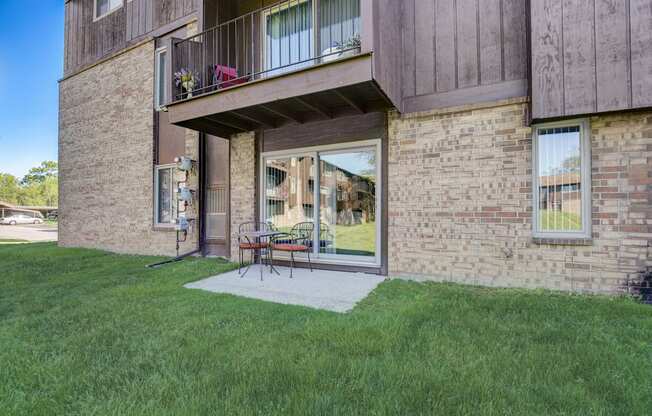 a patio in front of a brick building with a sliding.  Maple Place Apartments - Southfield MI glass door