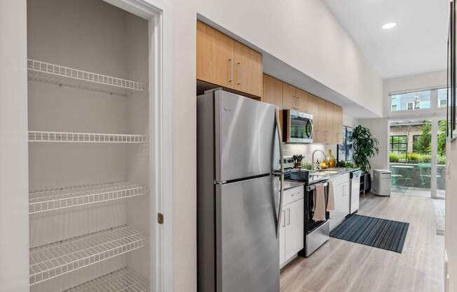 A modern kitchen with a refrigerator and an open door to a pantry.