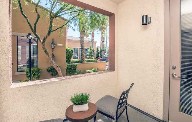 a patio with a chair and a table and a large window