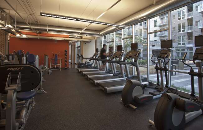 a gym with cardio equipment and windows in a building