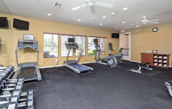 A gym with treadmills, weights, and exercise equipment.