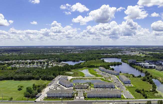 A large building complex sits in the middle of a green field with a river running through it.