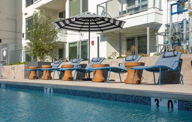 a poolside deck with lounge chairs and an umbrella
