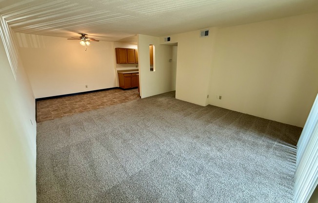 A room with a carpeted floor and a ceiling fan.