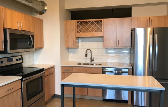 Open Kitchen with Wooden Cabinetry, Stainless Steal Appliances and White Counter Tops at Minneapolis Apartment