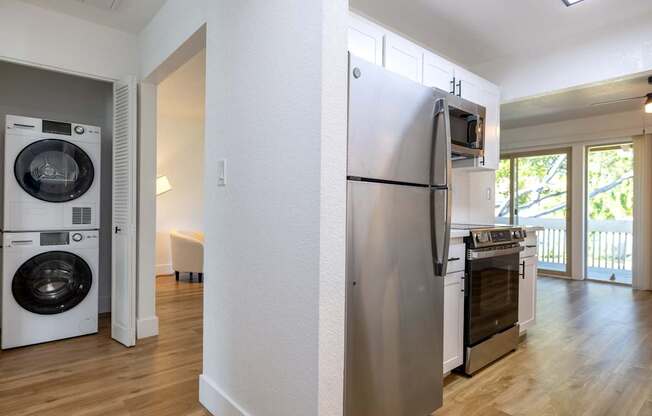 A white refrigerator is in a kitchen next to a washer and dryer.