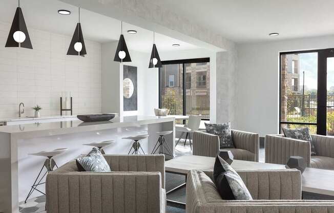 A modern living room with grey couches and a white kitchen.