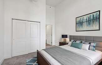 A bedroom with a bed, nightstand, and a painting on the wall.