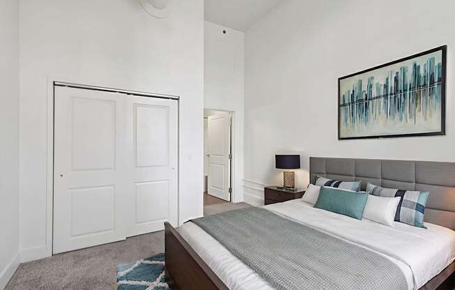 A bedroom with a bed, nightstand, and a painting on the wall.
