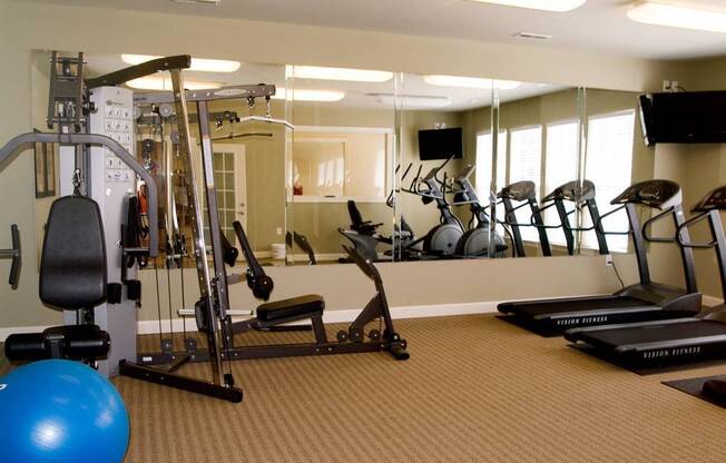 A gym with a blue ball, treadmills, and exercise equipment.