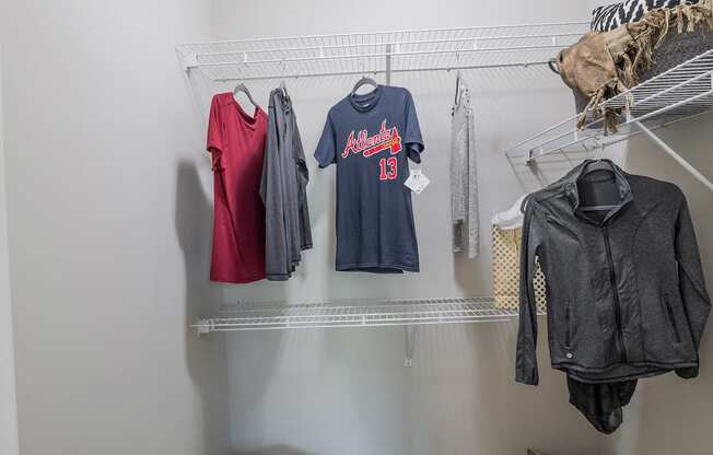 A row of clothes hangs on a white shelf.