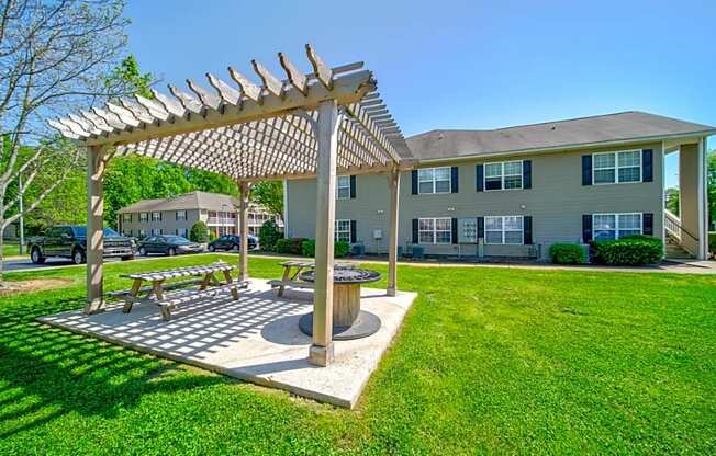 a picnic area with a pergola in front of an apartment building