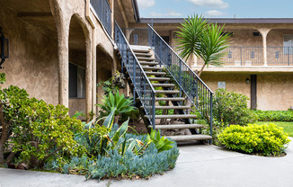 a staircase with a black railing and green plants in front of it