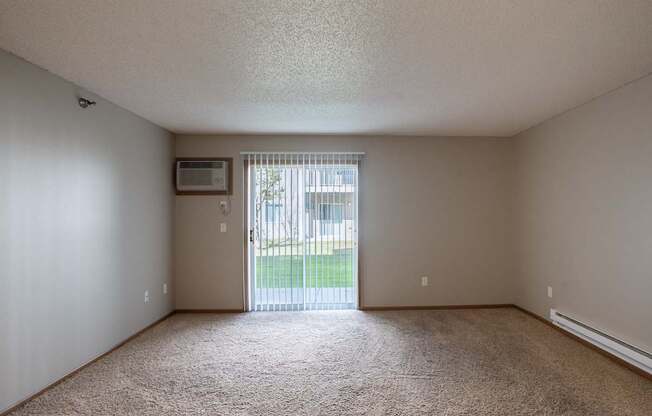 an empty living room with a sliding glass door to a yard