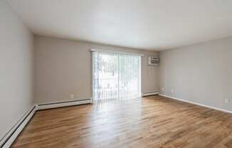 an empty living room with wood flooring and a sliding glass door