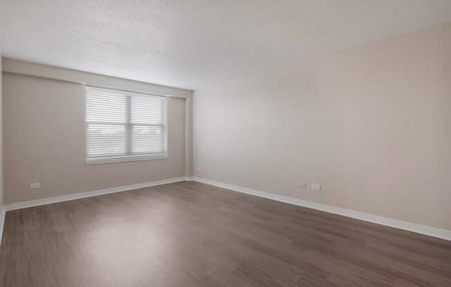an empty bedroom room with wooden floors and a window