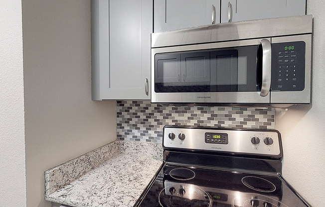 Modern kitchen with sleek stainless steel appliances, elegant tiled backsplash, and polished granite countertops.
