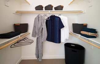 a walk in closet with wooden shelves and racks with clothes and baskets