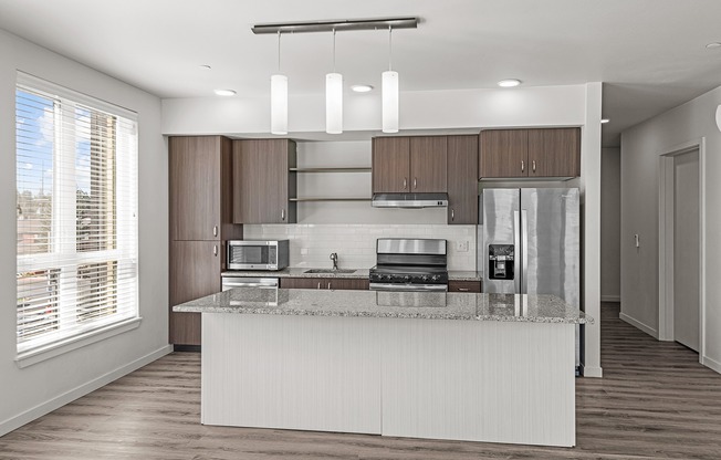 Large kitchen with stainless steel appliances, granite countertops, large windows and a kitchen island