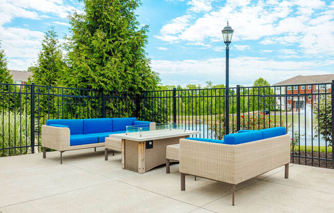 a patio with couches and a table in front of a fence