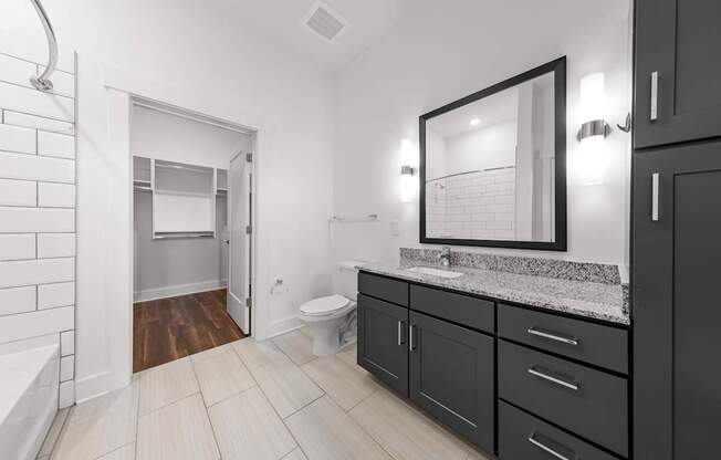 A bathroom with a toilet, sink, and a mirror.