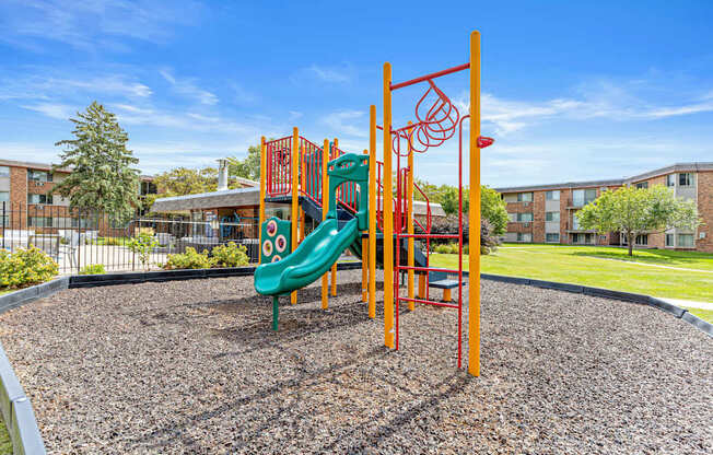 A playground with a green slide and orange climbing structure.