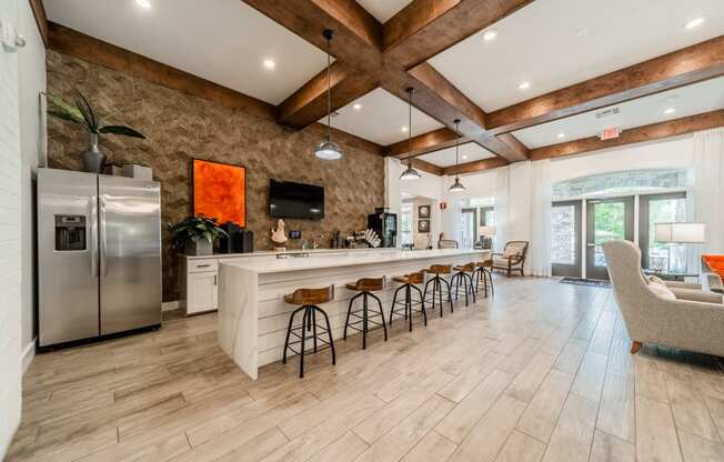 a kitchen with a long island with bar chairs and a refrigerator
