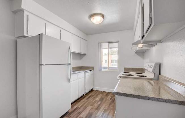 A kitchen with white appliances and a window.