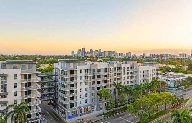 an aerial view of apartment buildings with palm trees and a city skyline in the background