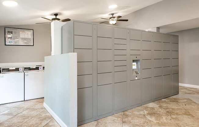 A laundry room with a washer and dryer, a fan, and a wall of lockers.