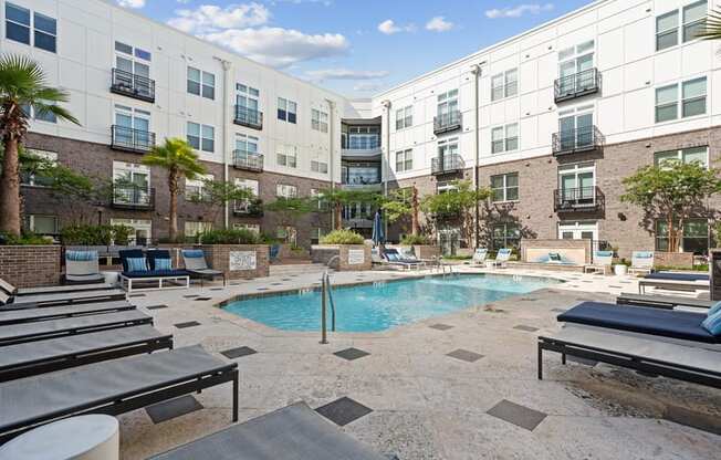 a swimming pool with lounge chairs in front of an apartment building