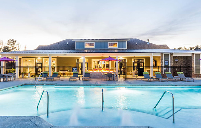 a swimming pool with chairs and a building in the background