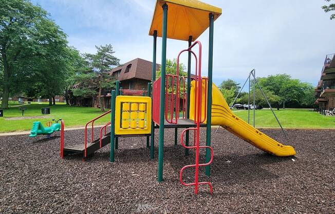 a playground with a yellow swing set in a park