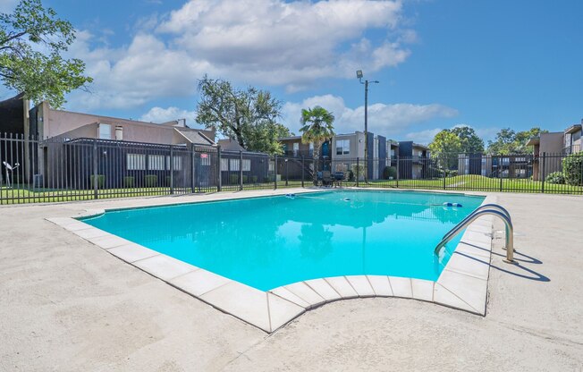 A rectangular pool with a white border and a black fence around it at The Drake in Bossier City, LA