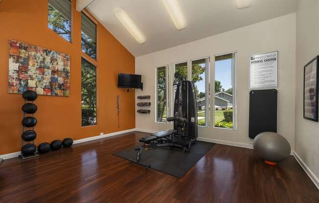 a home gym with hardwood floors and orange walls