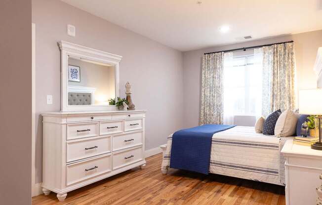A bedroom with a bed, dresser, and nightstand.