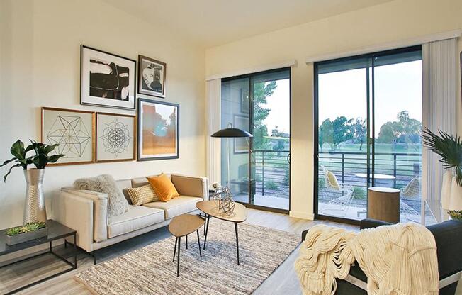 Apartments Old Town Scottsdale - Spacious Living Room with Large Window, Wood Flooring, and Sliding Glass Door Leading to he Patio