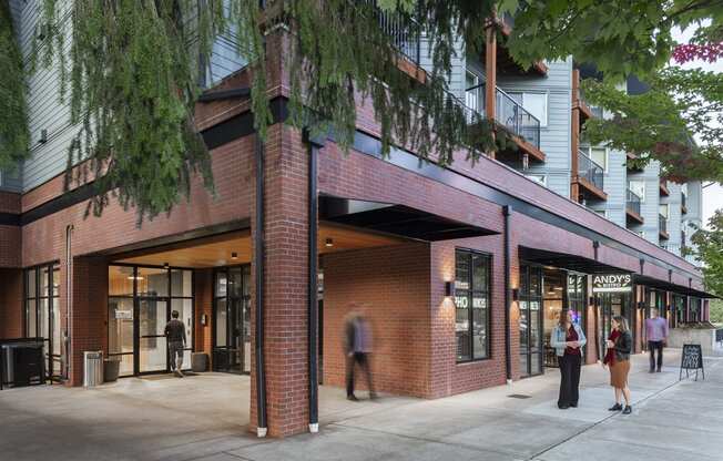 Corner exterior with trees, balconies, and people outside retail spaces at 6 Wood Flats, Lacey, 98503
