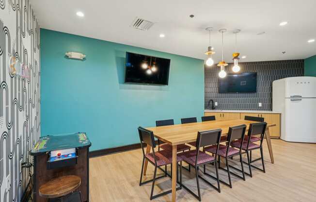 a dining room with a wooden table and chairs and a blue wall with a television