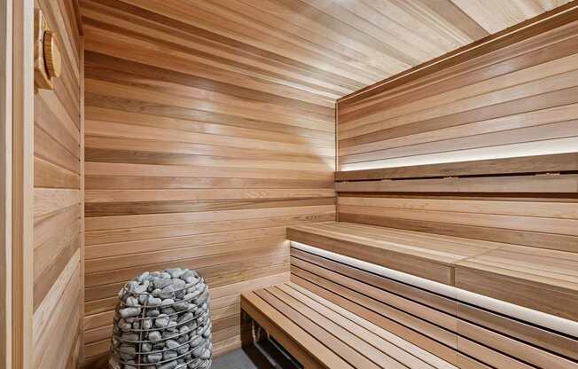 A wooden sauna with benches and a stone bucket.