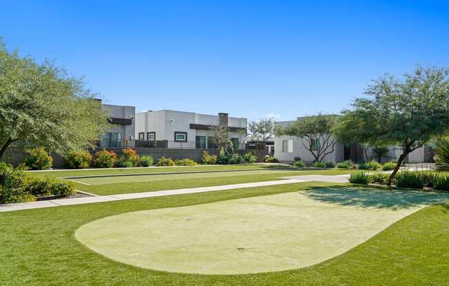 a yard with grass and trees and buildings in the background