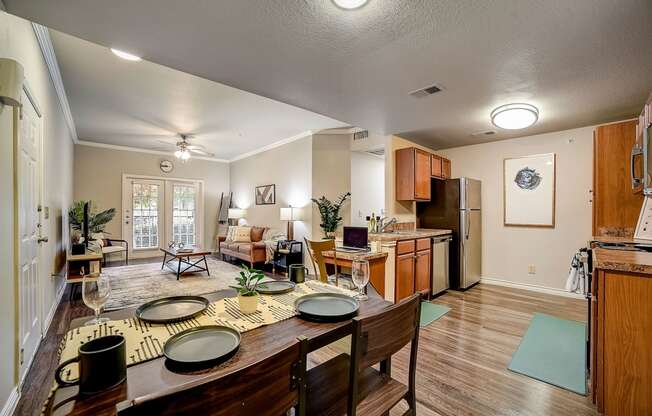 a dining area with a wooden table and chairs and a kitchen in the background